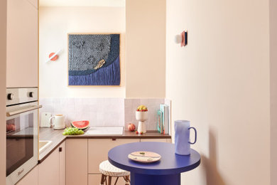 Idée de décoration pour une petite cuisine bohème en L avec un évier posé, un placard à porte plane, des portes de placard blanches, une crédence blanche, aucun îlot, un sol marron et un plan de travail marron.