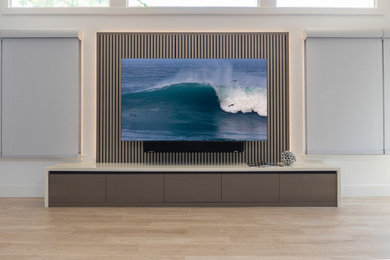 Example of a large trendy open concept light wood floor, beige floor, vaulted ceiling and wood wall family room design in San Francisco with gray walls, no fireplace and a media wall