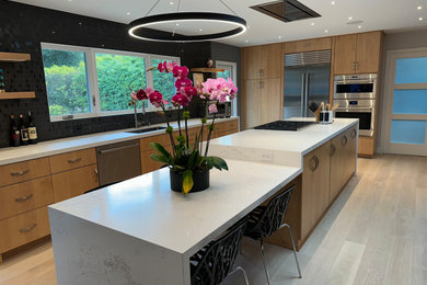 Inspiration for a large contemporary galley light wood floor and beige floor eat-in kitchen remodel in San Francisco with a single-bowl sink, flat-panel cabinets, light wood cabinets, quartz countertops, black backsplash, stainless steel appliances, an island and white countertops