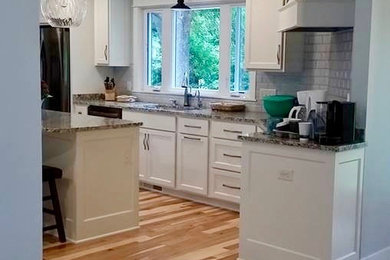 Mid-sized traditional u-shaped separate kitchen in Minneapolis with an undermount sink, shaker cabinets, white cabinets, granite benchtops, stainless steel appliances, light hardwood floors, with island, beige floor, grey benchtop and grey splashback.