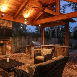 Large traditional backyard patio in New Orleans with an outdoor kitchen, brick pavers and a roof extension.
