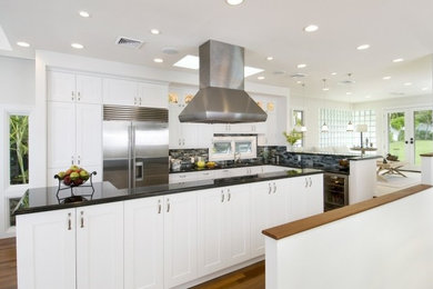 Example of a mid-sized minimalist l-shaped medium tone wood floor eat-in kitchen design in San Francisco with shaker cabinets, white cabinets, granite countertops, multicolored backsplash, matchstick tile backsplash, stainless steel appliances and an island