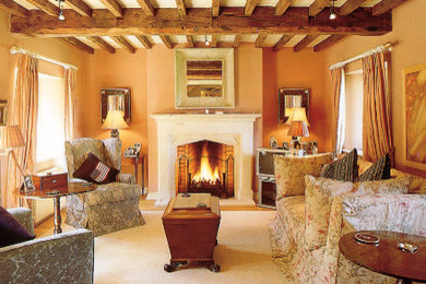 Photo of a large vintage living room in Gloucestershire with carpet, a stacked stone fireplace surround and exposed beams.