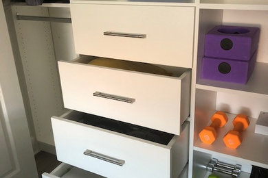 Diseño de armario unisex actual pequeño con armarios con paneles lisos, puertas de armario blancas, suelo laminado y suelo marrón