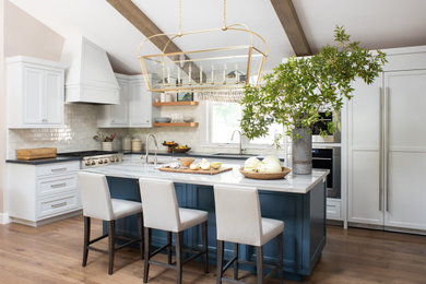 Example of a transitional medium tone wood floor and vaulted ceiling kitchen design in San Francisco with blue cabinets and an island