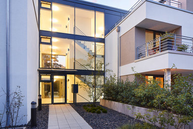 Photo of a large contemporary front door in Frankfurt with white walls, concrete floors, a single front door, a glass front door and grey floor.