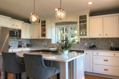 Mid-sized transitional l-shaped medium tone wood floor and brown floor eat-in kitchen photo in Other with a farmhouse sink, recessed-panel cabinets, white cabinets, marble countertops, gray backsplash, mosaic tile backsplash, stainless steel appliances and an island