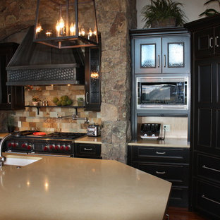 Large traditional kitchen pantry remodeling - Inspiration for a large timeless l-shaped medium tone wood floor kitchen pantry remodel in Denver with a farmhouse sink, flat-panel cabinets, black cabinets, quartzite countertops, multicolored backsplash, stone tile backsplash, paneled appliances and an island