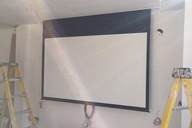 Inspiration for a large modern open plan home cinema in London with grey walls and a projector screen.