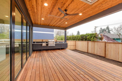 Example of a mid-sized trendy backyard outdoor kitchen deck design in Portland with a roof extension