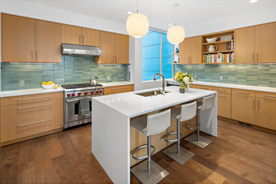 Inspiration for a mid-century modern l-shaped medium tone wood floor and brown floor kitchen remodel in Seattle with medium tone wood cabinets, stone tile backsplash, an island, white countertops, an undermount sink, flat-panel cabinets and gray backsplash