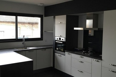 Diseño de cocina contemporánea de tamaño medio con fregadero bajoencimera, puertas de armario blancas, encimera de laminado, salpicadero verde, electrodomésticos de acero inoxidable y una isla