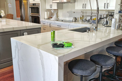 Example of a mid-sized transitional u-shaped medium tone wood floor and brown floor eat-in kitchen design in Phoenix with an undermount sink, shaker cabinets, white cabinets, quartz countertops, stainless steel appliances, an island and white countertops
