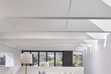 Exemple d'un salon tendance ouvert avec un mur blanc, un sol gris, poutres apparentes et un plafond voûté.