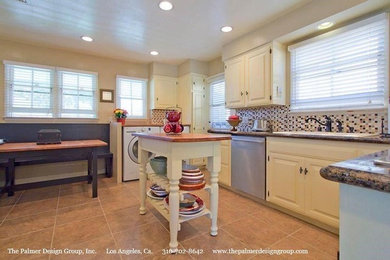Example of a country porcelain tile kitchen design with a drop-in sink, raised-panel cabinets, granite countertops, multicolored backsplash, mosaic tile backsplash, stainless steel appliances and an island