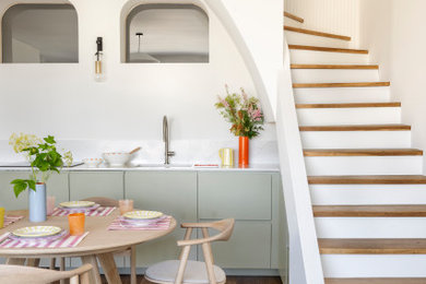 Réalisation d'une cuisine ouverte linéaire et blanche et bois design de taille moyenne avec un évier encastré, un placard avec porte à panneau encastré, des portes de placards vertess, un plan de travail en quartz, une crédence blanche, une crédence en quartz modifié, aucun îlot, un sol marron, un plan de travail blanc et fenêtre au-dessus de l'évier.