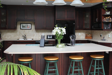 Kitchen - large traditional u-shaped ceramic tile and beige floor kitchen idea in Toronto with a drop-in sink, shaker cabinets, dark wood cabinets, solid surface countertops, beige backsplash, stone tile backsplash, black appliances and an island