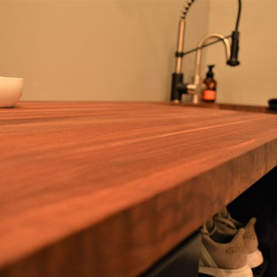 他の地域の小さいカントリー風おしゃれな洗濯室 (アンダーカウンターシンク、シェーカースタイル扉のキャビネット、濃色木目調キャビネット、木材カウンター、ベージュの壁、セラミックタイルの床、上下配置の洗濯機・乾燥機、ベージュの床、茶色いキッチンカウンター) の写真