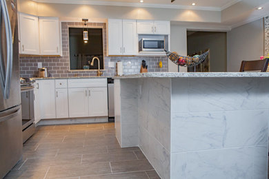 Enclosed kitchen - large modern l-shaped enclosed kitchen idea in Philadelphia with an undermount sink, shaker cabinets, white cabinets, granite countertops, gray backsplash, stainless steel appliances, an island and subway tile backsplash