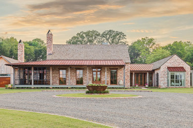 Example of a farmhouse one-story brick house exterior design in New Orleans with a mixed material roof