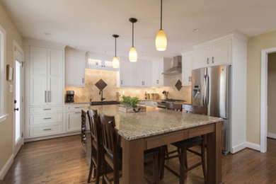 Inspiration for a mid-sized transitional l-shaped kitchen in Raleigh with a farmhouse sink, stainless steel appliances, with island, brown floor, white cabinets, granite benchtops, beige splashback, porcelain splashback, beaded inset cabinets, multi-coloured benchtop and dark hardwood floors.