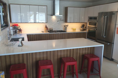 Inspiration for a mid-sized contemporary u-shaped enclosed kitchen remodel in New York with an undermount sink, flat-panel cabinets, white cabinets, solid surface countertops, white backsplash, stainless steel appliances and a peninsula