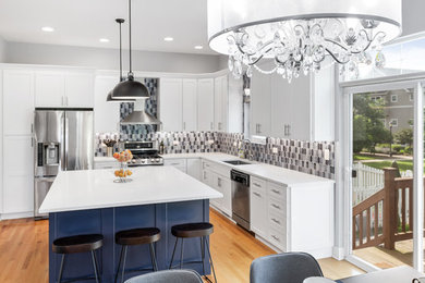 Photo of a mid-sized contemporary l-shaped eat-in kitchen in Chicago with an undermount sink, shaker cabinets, white cabinets, quartz benchtops, multi-coloured splashback, mosaic tile splashback, stainless steel appliances, medium hardwood floors, with island and white benchtop.