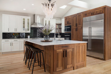 Mid-sized transitional galley medium tone wood floor kitchen photo in Denver with an undermount sink, shaker cabinets, medium tone wood cabinets, quartz countertops, black backsplash, subway tile backsplash, stainless steel appliances, an island and white countertops