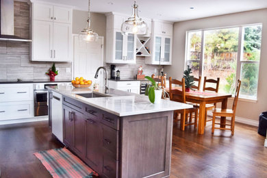 Mid-sized transitional l-shaped medium tone wood floor eat-in kitchen photo in Denver with a single-bowl sink, shaker cabinets, white cabinets, quartz countertops, gray backsplash, porcelain backsplash, stainless steel appliances, an island and white countertops
