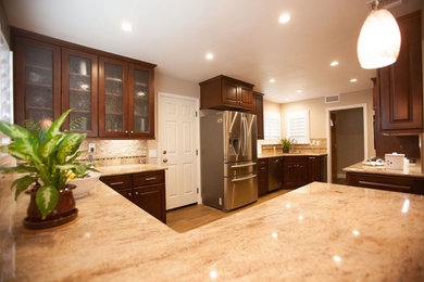 Large elegant u-shaped dark wood floor eat-in kitchen photo in Los Angeles with an undermount sink, raised-panel cabinets, dark wood cabinets, granite countertops, beige backsplash, stone tile backsplash, stainless steel appliances and no island