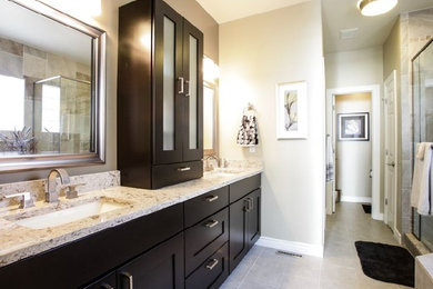 Design ideas for a large transitional master bathroom in Denver with shaker cabinets, brown cabinets, an alcove shower, gray tile, ceramic tile, beige walls, limestone floors, an undermount sink, engineered quartz benchtops, beige floor and a hinged shower door.