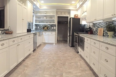 Photo of a mid-sized transitional galley eat-in kitchen in Dallas with a farmhouse sink, shaker cabinets, white cabinets, granite benchtops, multi-coloured splashback, glass tile splashback, stainless steel appliances, laminate floors, beige floor and no island.