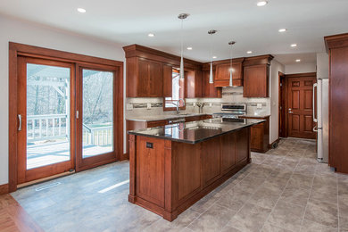 Eat-in kitchen - mid-sized transitional l-shaped porcelain tile and gray floor eat-in kitchen idea in Cleveland with an undermount sink, recessed-panel cabinets, dark wood cabinets, granite countertops, beige backsplash, subway tile backsplash, stainless steel appliances, an island and beige countertops
