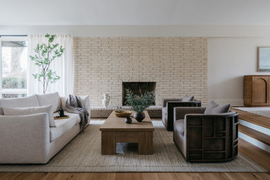 Large 1950s open concept medium tone wood floor and brown floor living room photo in Chicago with beige walls, a standard fireplace and a brick fireplace