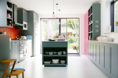 Photo of a large contemporary galley open plan kitchen in Cambridgeshire with shaker cabinets, grey cabinets, laminate countertops, orange splashback, ceramic splashback, stainless steel appliances, porcelain flooring, an island, white floors and white worktops.