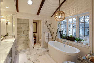 Large transitional master bathroom in Omaha with an undermount sink, recessed-panel cabinets, white cabinets, marble benchtops, a freestanding tub, an alcove shower, a two-piece toilet, white tile, stone tile, white walls and marble floors.