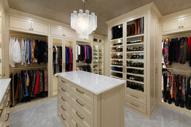 Example of a large transitional gender-neutral marble floor, white floor and wallpaper ceiling walk-in closet design in Dallas with beaded inset cabinets and beige cabinets