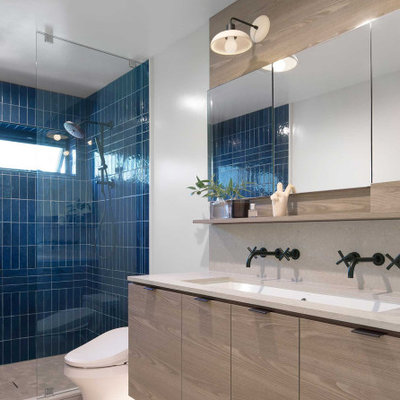 Example of a large trendy master beige floor and double-sink alcove shower design in Hawaii with flat-panel cabinets, light wood cabinets, white walls, a floating vanity, a wall-mount sink, quartz countertops, a hinged shower door and beige countertops