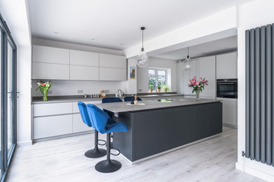 Contemporary kitchen in Sussex with flat-panel cabinets, grey cabinets, an island and grey worktops.