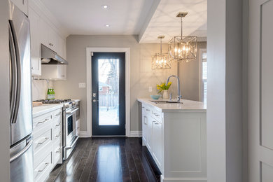 Inspiration for a small transitional galley dark wood floor eat-in kitchen remodel in Toronto with an undermount sink, shaker cabinets, white cabinets, quartz countertops, white backsplash, stone slab backsplash, stainless steel appliances and an island