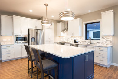 Mid-sized minimalist l-shaped medium tone wood floor eat-in kitchen photo in Minneapolis with an undermount sink, recessed-panel cabinets, white cabinets, marble countertops, gray backsplash, matchstick tile backsplash, stainless steel appliances and an island