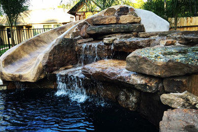 Example of a mid-sized arts and crafts backyard stone and round lap water slide design in Houston