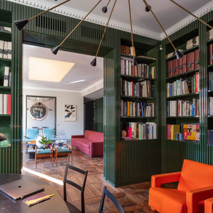 Inredning av ett modernt stort arbetsrum, med ett bibliotek, gröna väggar, mörkt trägolv, en standard öppen spis, en spiselkrans i metall, ett fristående skrivbord och brunt golv