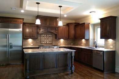 Large elegant u-shaped dark wood floor eat-in kitchen photo in Kansas City with an undermount sink, raised-panel cabinets, dark wood cabinets, granite countertops, beige backsplash, ceramic backsplash, stainless steel appliances and an island