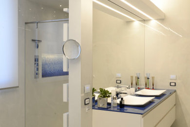 Ejemplo de cuarto de baño doble y flotante moderno con puertas de armario blancas, ducha a ras de suelo, baldosas y/o azulejos beige, paredes blancas, suelo blanco y encimeras azules