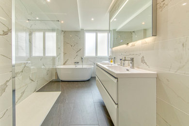 Cette image montre une salle d'eau minimaliste avec des portes de placard blanches, une douche ouverte, WC séparés, un carrelage blanc, du carrelage en marbre, une vasque, un sol gris, aucune cabine, une fenêtre, meuble double vasque, meuble-lavabo suspendu et un mur en pierre.