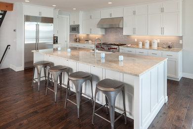 This is an example of a large transitional single-wall eat-in kitchen in Seattle with a farmhouse sink, shaker cabinets, white cabinets, marble benchtops, beige splashback, subway tile splashback, stainless steel appliances, dark hardwood floors, with island and brown floor.