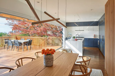 Inspiration for a large 1950s l-shaped medium tone wood floor and brown floor open concept kitchen remodel in San Francisco with an undermount sink, flat-panel cabinets, blue cabinets, quartz countertops, white backsplash, subway tile backsplash, paneled appliances, an island and white countertops