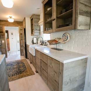 Modelo de cocina de galera, de estilo americano, de tamaño medio, con fregadero sobremueble, armarios con paneles lisos, puertas de armario con efecto envejecido, encimera de mármol, salpicadero blanco, salpicadero de azulejos de cemento y suelo de madera clara