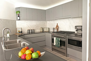 Inspiration for a mid-sized contemporary u-shaped open plan kitchen in Brisbane with a drop-in sink, flat-panel cabinets, grey cabinets, quartz benchtops, grey splashback, porcelain splashback, stainless steel appliances, terra-cotta floors, no island, beige floor and black benchtop.